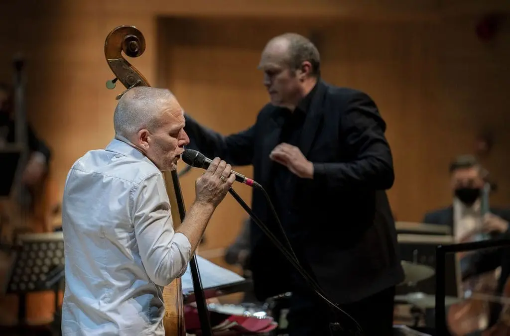 Orchestral show 2021 - Avishai Cohen singing on stage with Conductor on stage