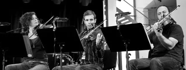 three musicians playing violins
